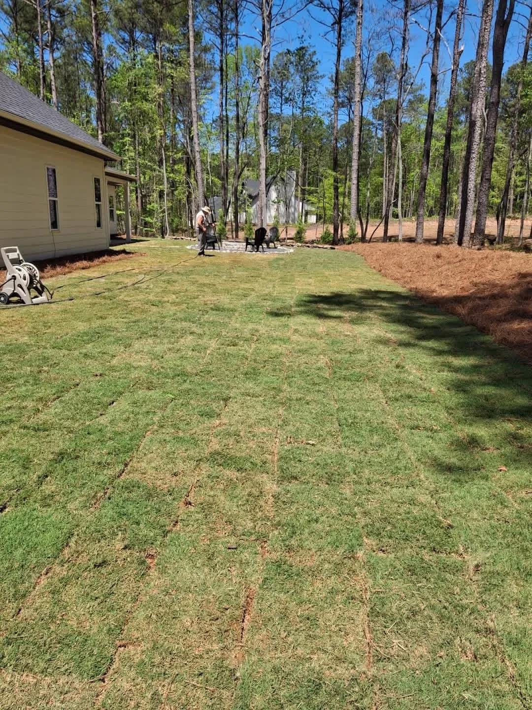 Fresh sod being laid beside a newly built house