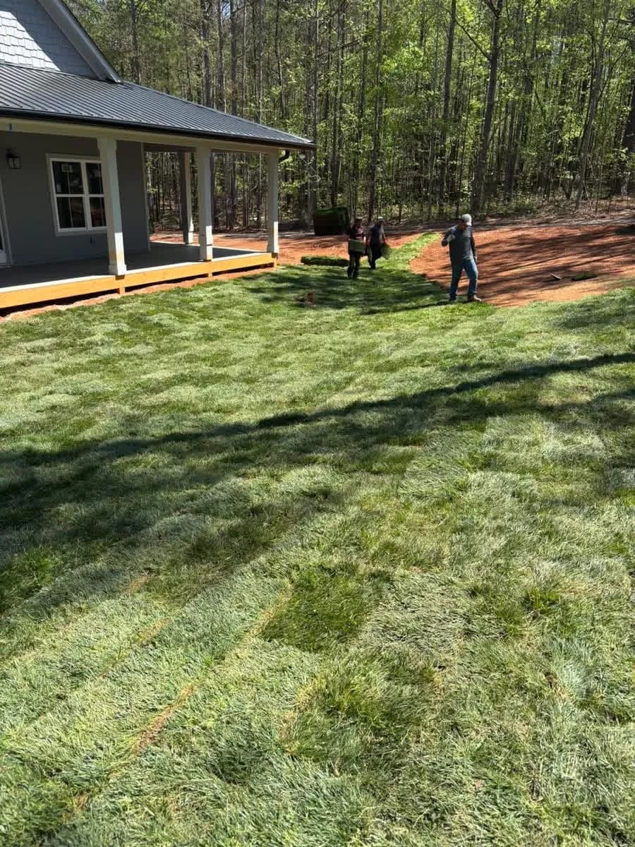 Newly laid sod lawn beside a blue farmhouse