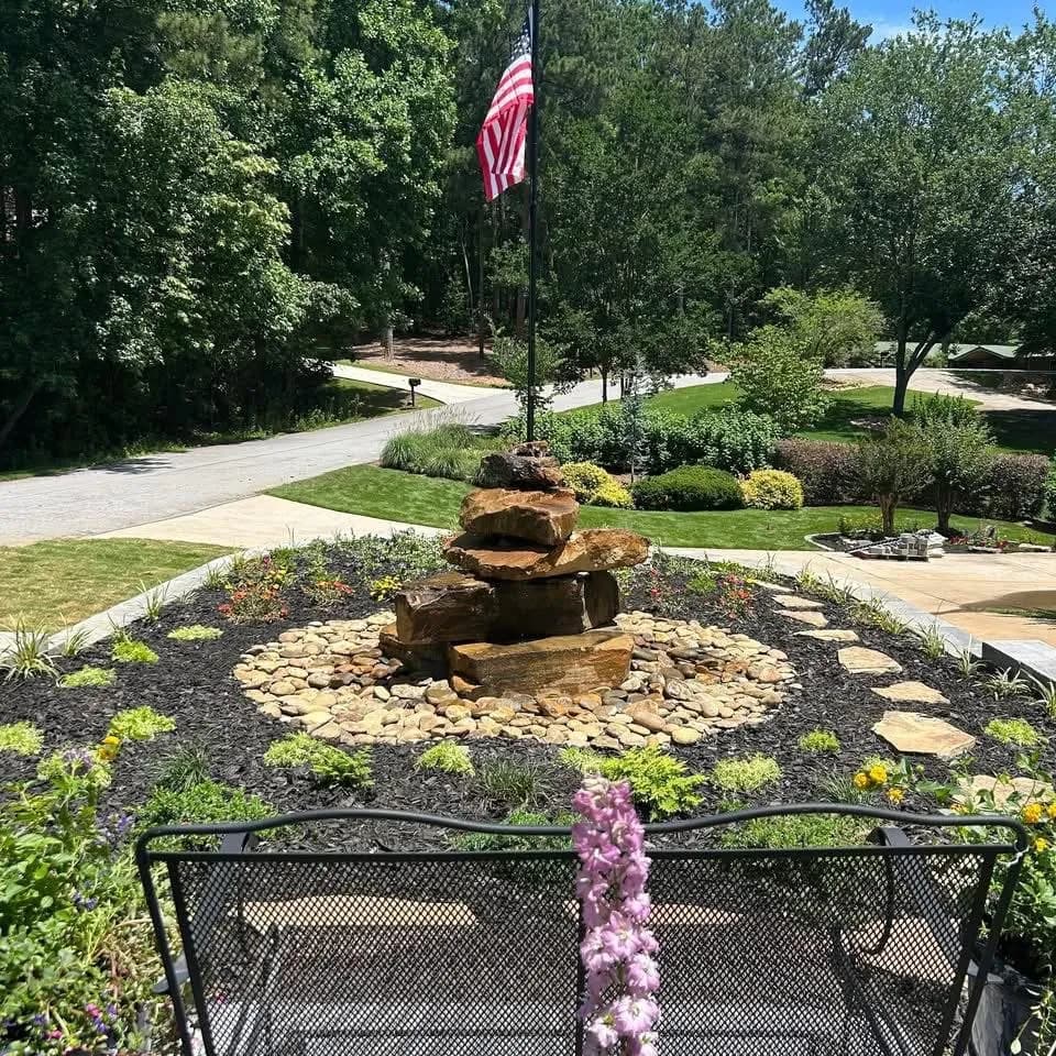 Stacked stone water feature in a mulched bed with flagstone steppers
